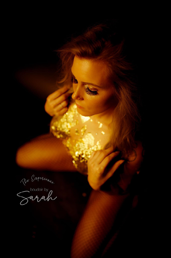 A woman in a gold dress is sitting in the dark.