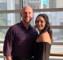 A man and a woman are posing for a picture in front of a window.