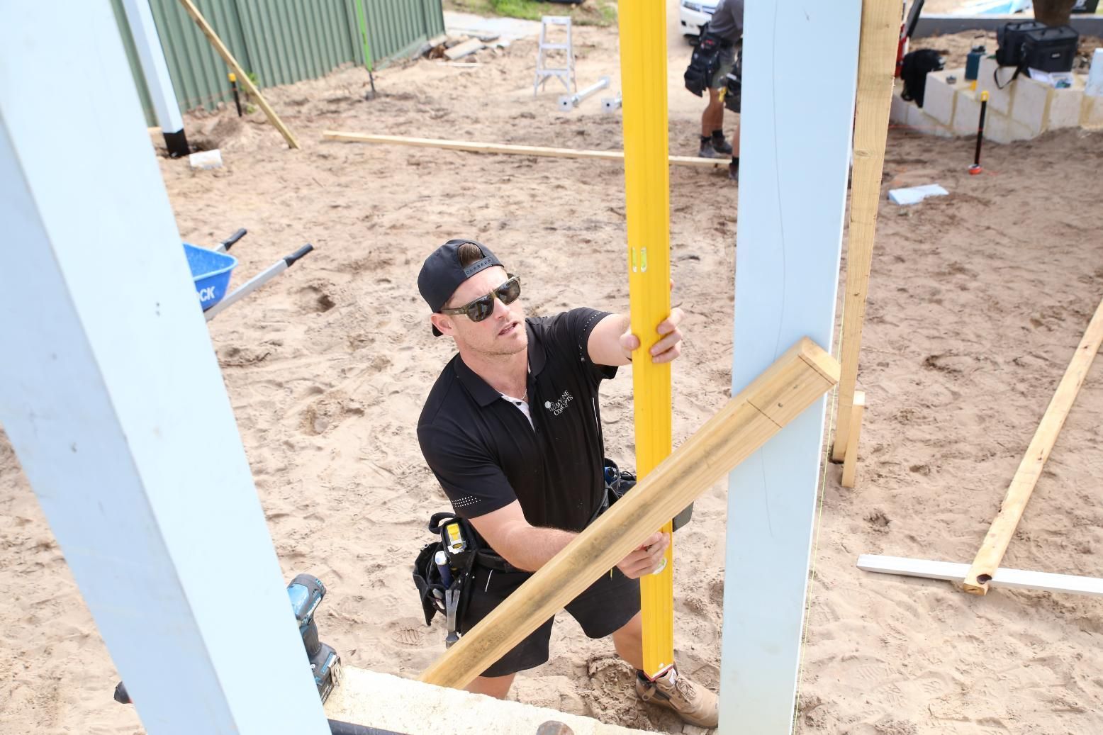 Worker in black shirt and sunglasses securing a yellow post at a construction site