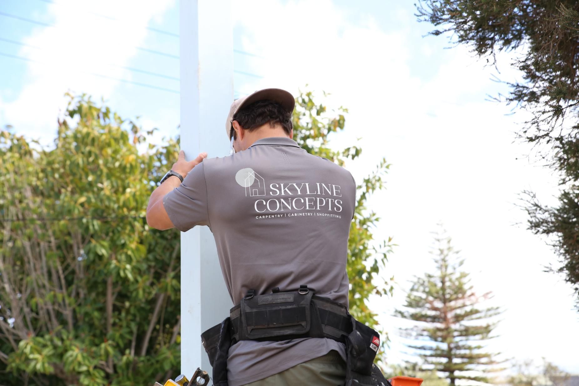 Worker in gray shirt and cap installing a white panel outdoors.