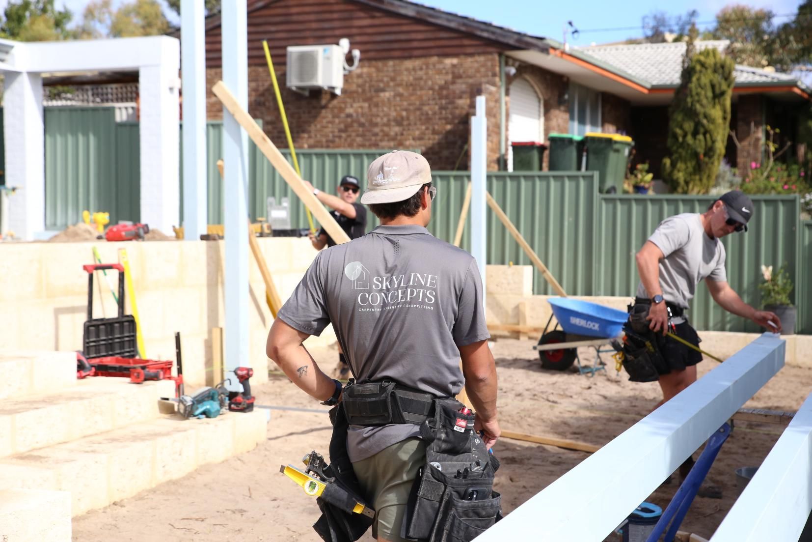 Construction workers installing long blue boards outside a house