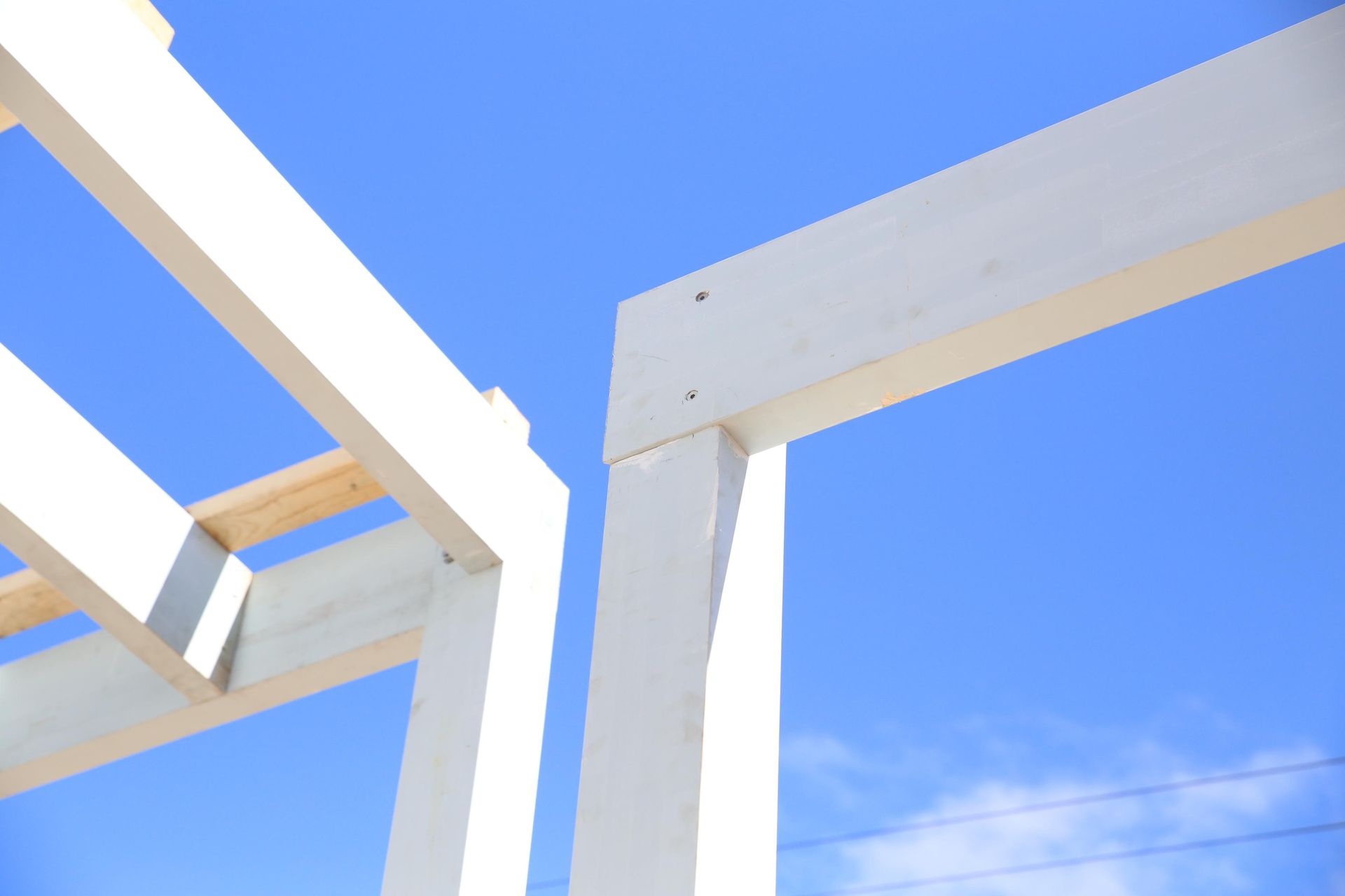 White architectural beams against a bright blue sky