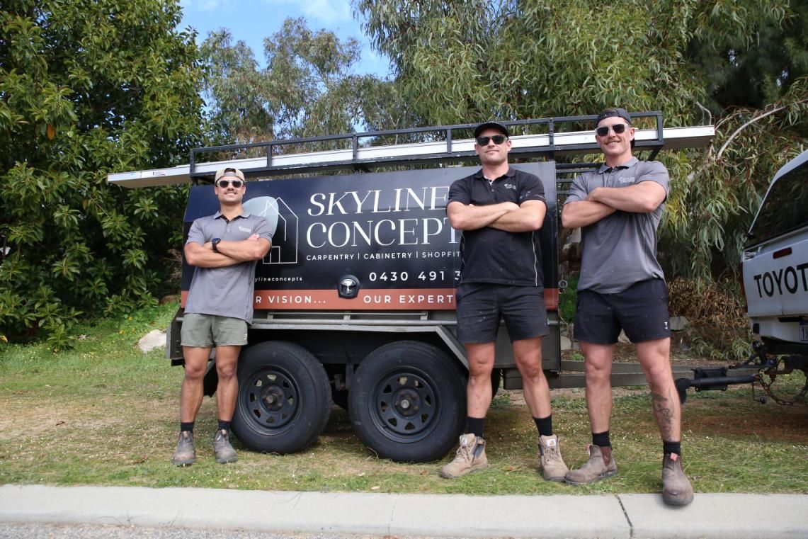 Three men standing arms crossed in front of a black trailer labeled “Skyline Concept” outdoors.