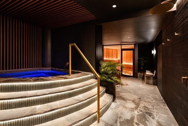 Modern spa with round hot tub, curved steps, and dim wood-paneled hallway with warm lighting