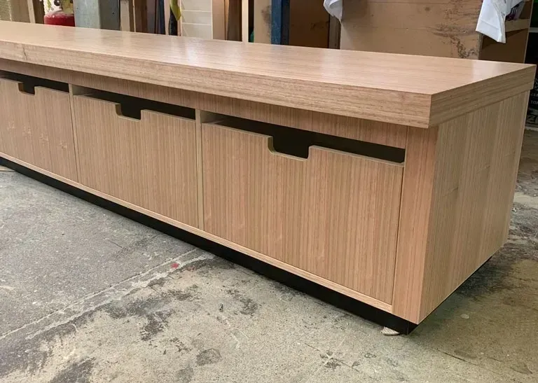 Wooden bench or storage unit with black slot openings in a workshop setting