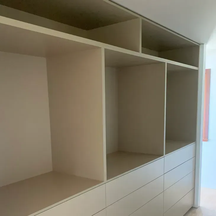 Built-in beige closet with open shelves and drawers in a bright room