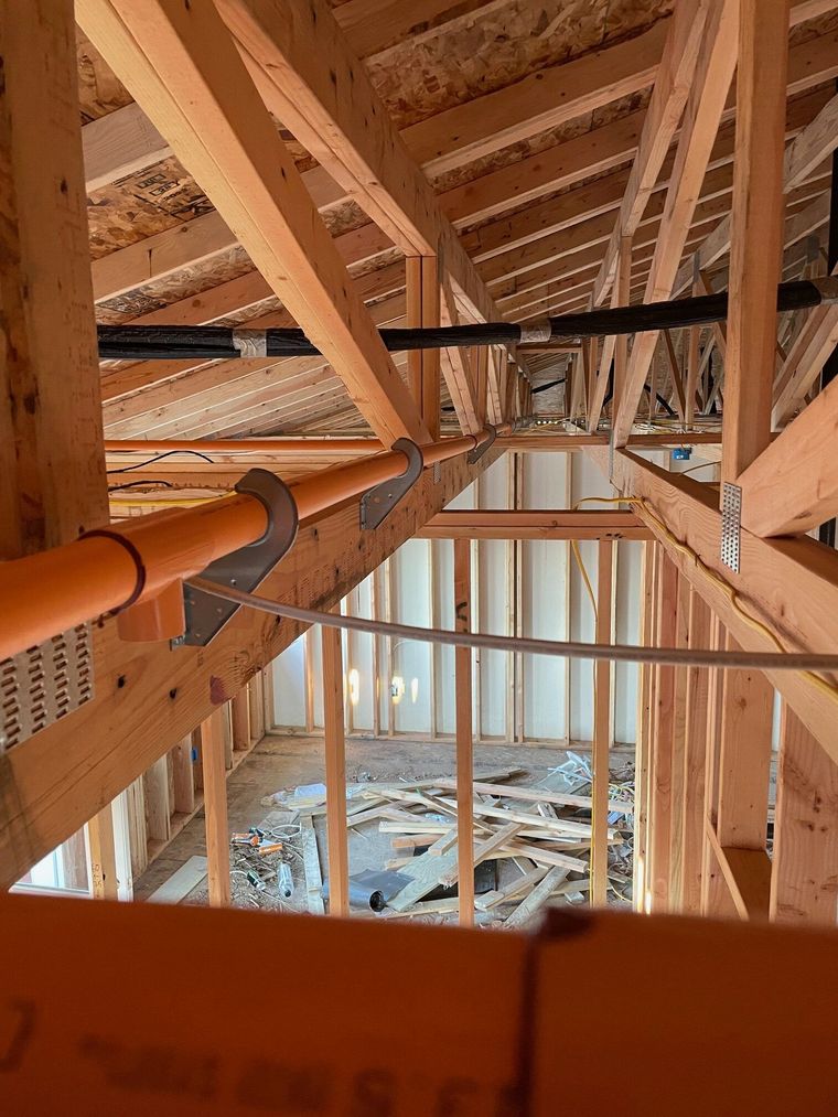 The inside of a building under construction with pipes hanging from the ceiling.