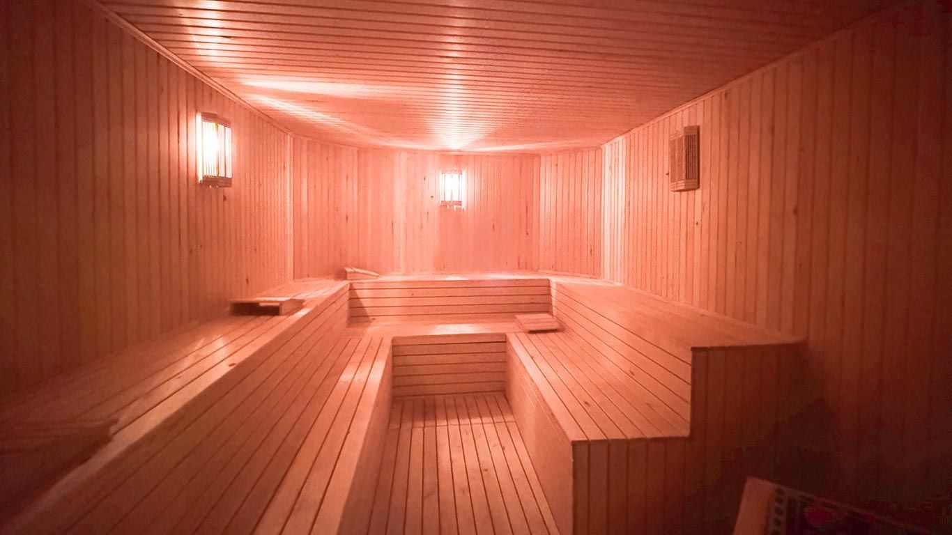 A wooden sauna with a lot of benches and lights on the ceiling. | Aldino Hotel