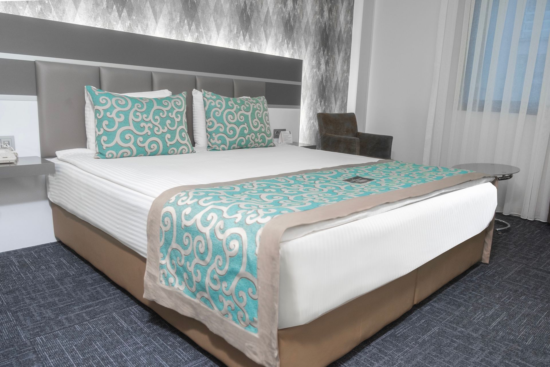 A hotel room with a large bed and a chair. Standard Room | Aldino Hotel