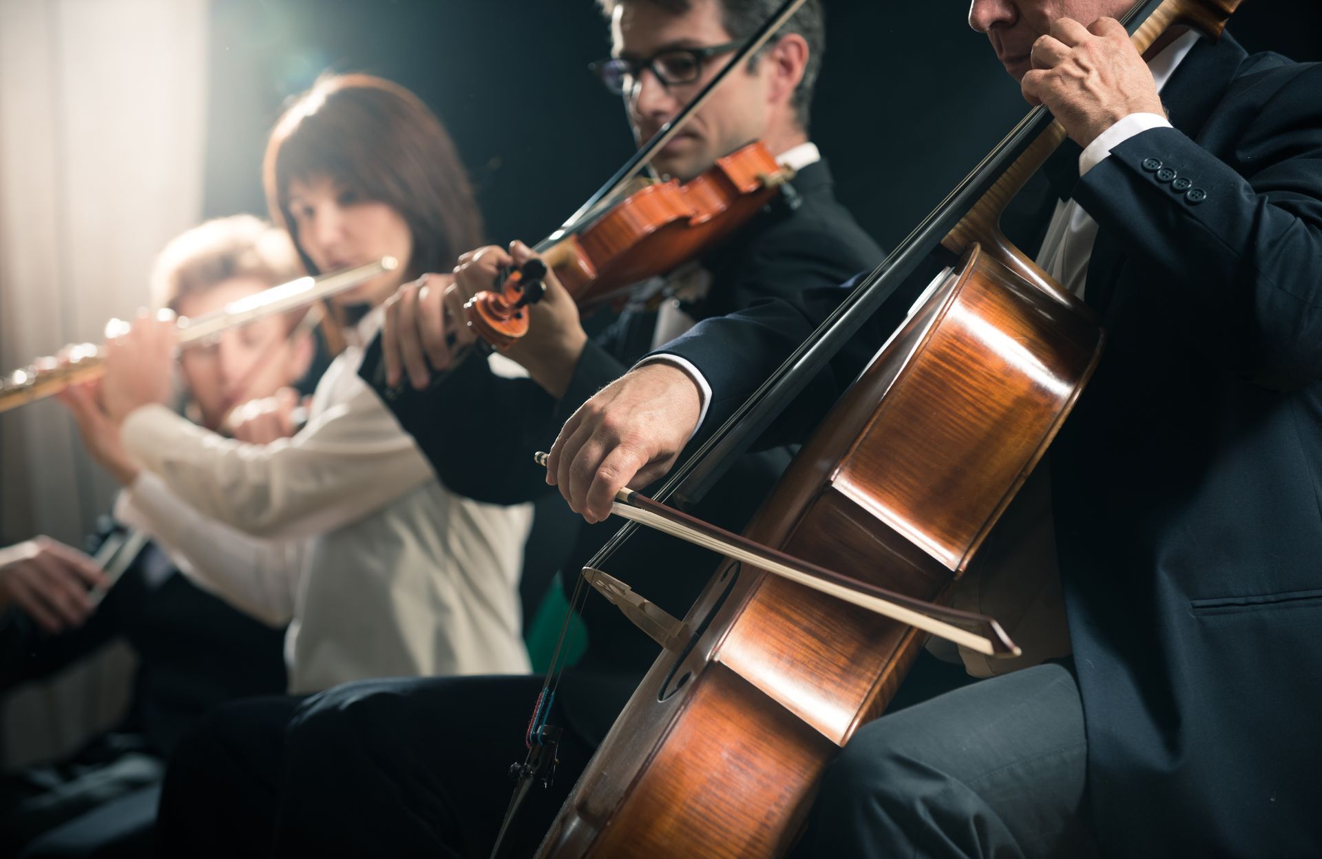 A group of people are playing violins and cello in an orchestra.