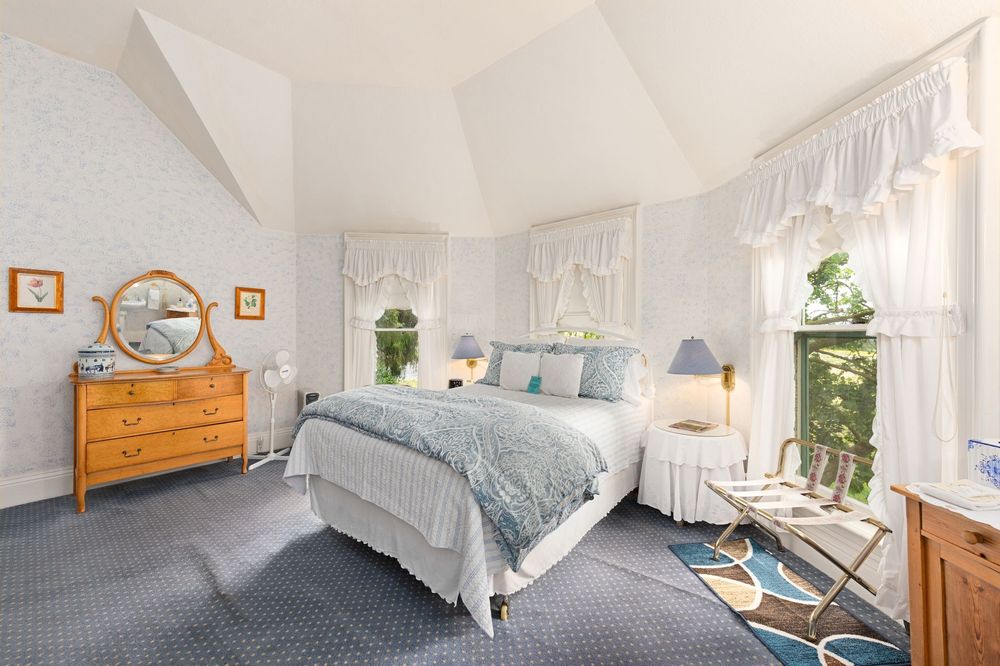 A bedroom with a bed , dresser , mirror and window.