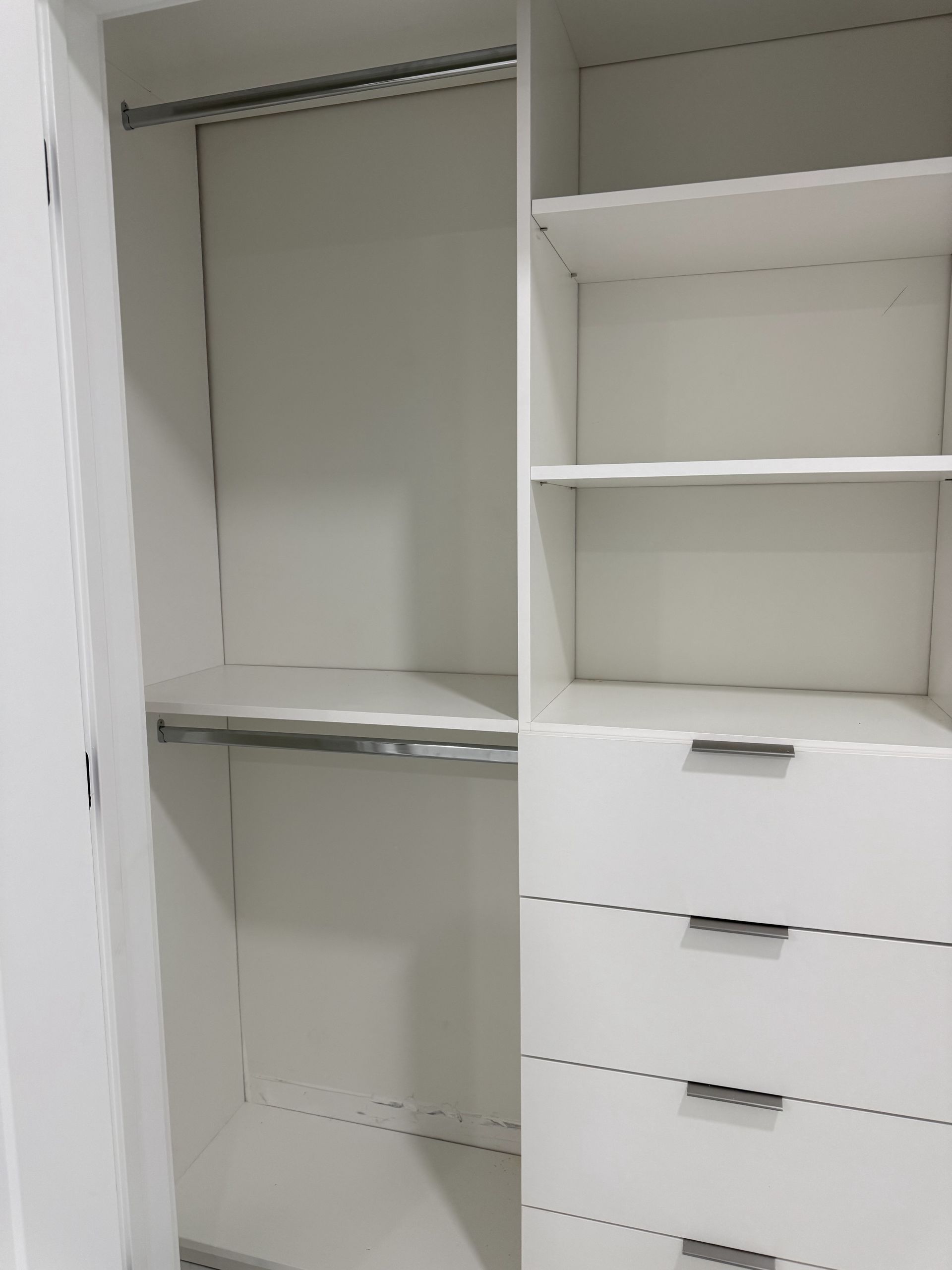 White built-in closet with shelves, drawers, and hanging rods.