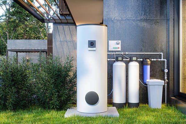 Outdoor water filtration system with white tanks and pipes beside a house under a patio cover.