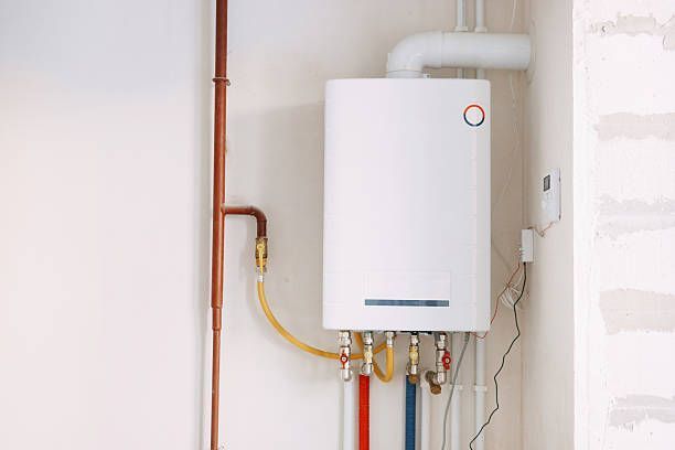 Wall-mounted white boiler with copper and yellow pipes in a utility room