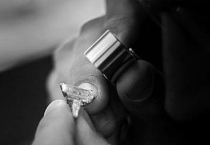 Close-up of a hand holding a diamond ring near a finger with a silver ring band