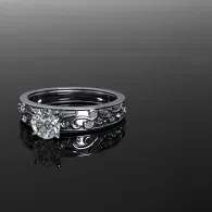 Silver ring with a large central gemstone on a glossy black reflective surface