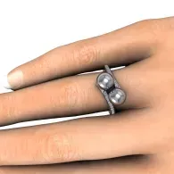 Close-up of a hand wearing a silver ring with two small pearls