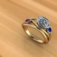 Gold ring with three gemstones: red, clear, and blue, on a wooden surface