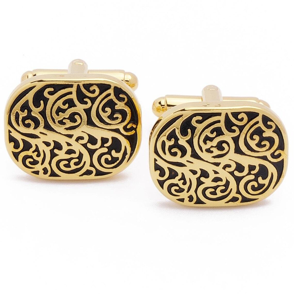 Pair of gold and black filigree cufflinks on a white background