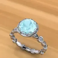 Silver ring with a large light blue gemstone on a wooden surface