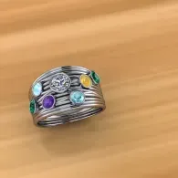 Silver ring with multicolored gemstones on a wooden surface