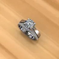 Silver diamond engagement ring with a matching band on a wooden surface