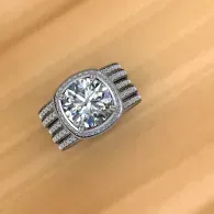 Silver ring with a large round clear gemstone and side stones on a wooden surface