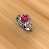 Silver ring with a red oval gemstone and small clear stones on a gold background