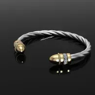 Twisted silver bracelet with gold and black bead accents on a dark background