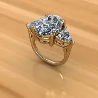 Gold ring with a large clear gemstone and two smaller side stones on a wooden surface