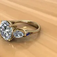 Gold ring with a large clear gemstone and smaller side stones on a wooden surface