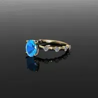 Blue gemstone ring with gold band and small clear stones on a black reflective background