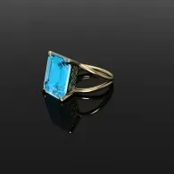 Gold ring with a large blue rectangular gemstone on a dark background