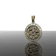 Gold circular pendant with a floral gemstone pattern and a mirrored reflection below