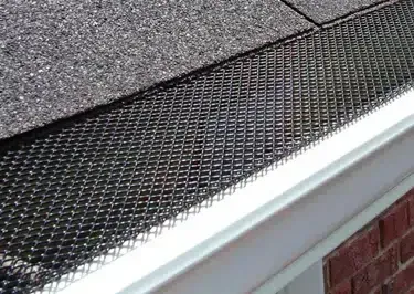 Gutter With Mesh Screen Installed Near a Roof — Over the Top Roofing Specialists in Narangba, QLD