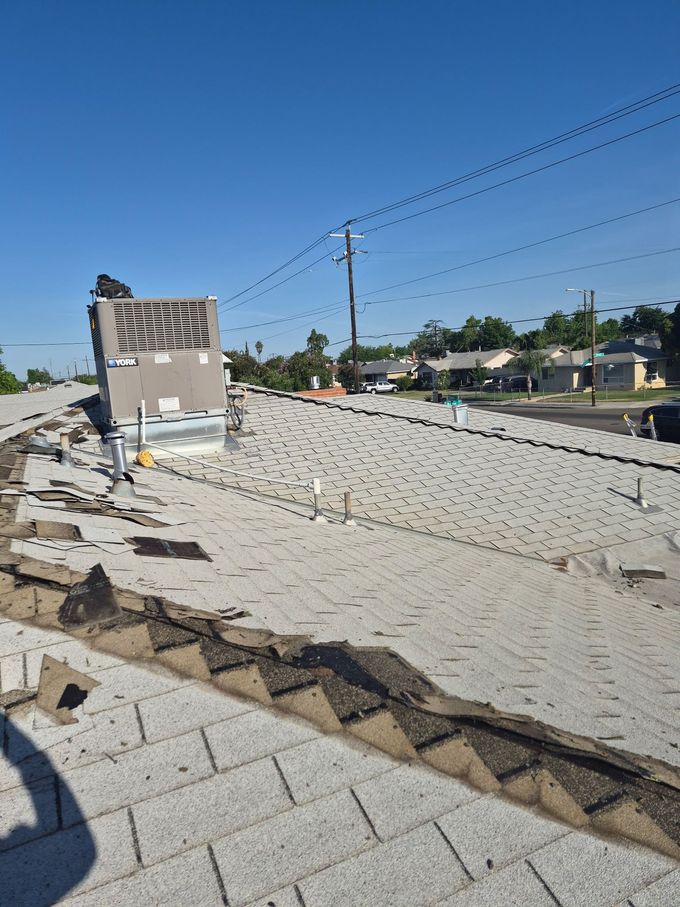 Broken rooftop with scattered debris and a utility pole under a clear blue sky.
