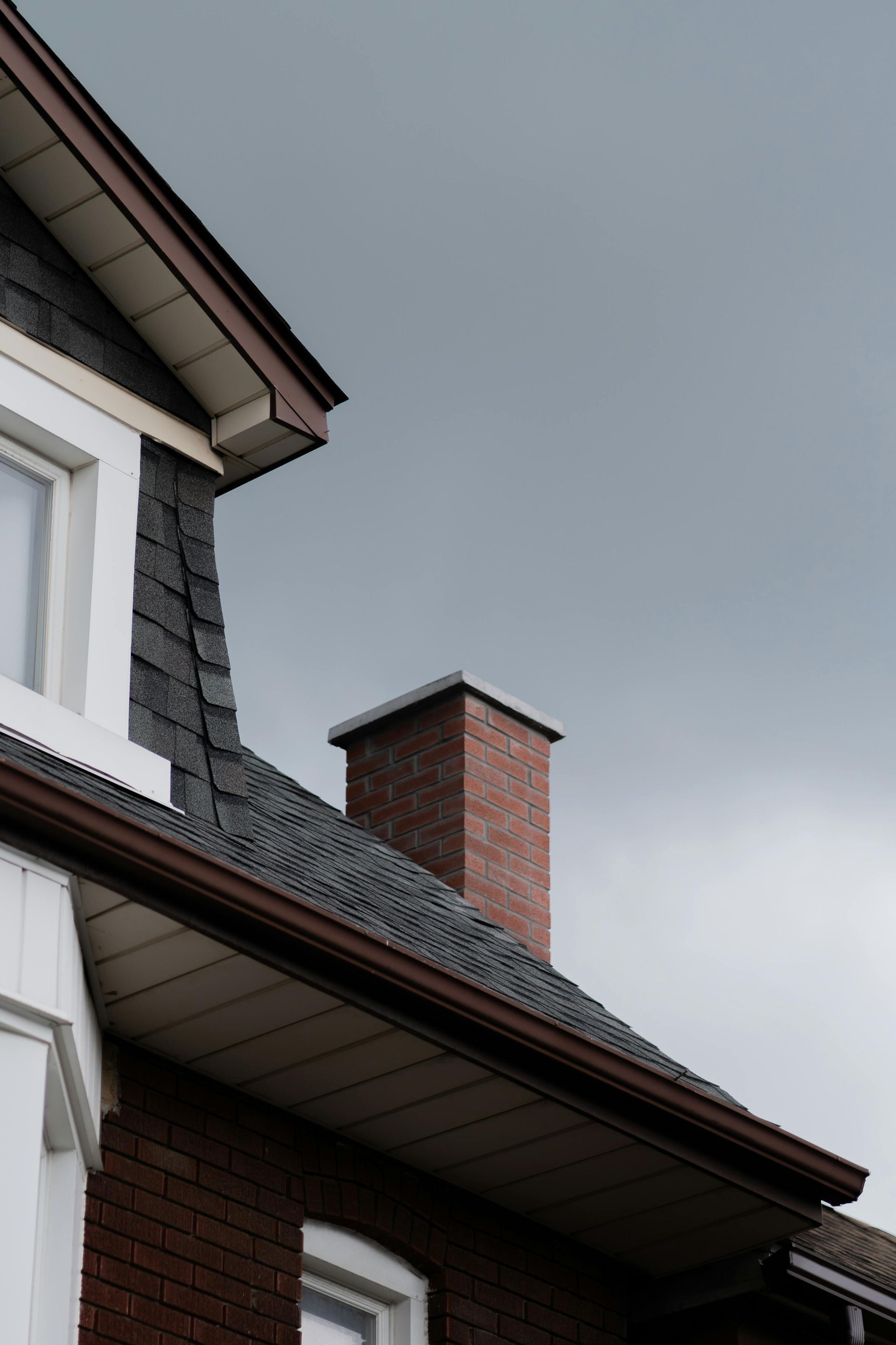 Brick chimney on a house roof against a gray sky