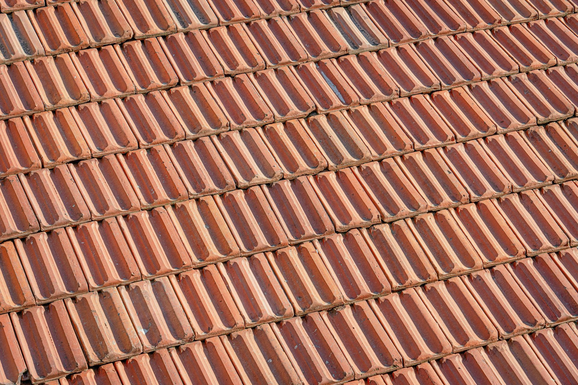 Rows of terracotta roof tiles in alternating red and tan stripes