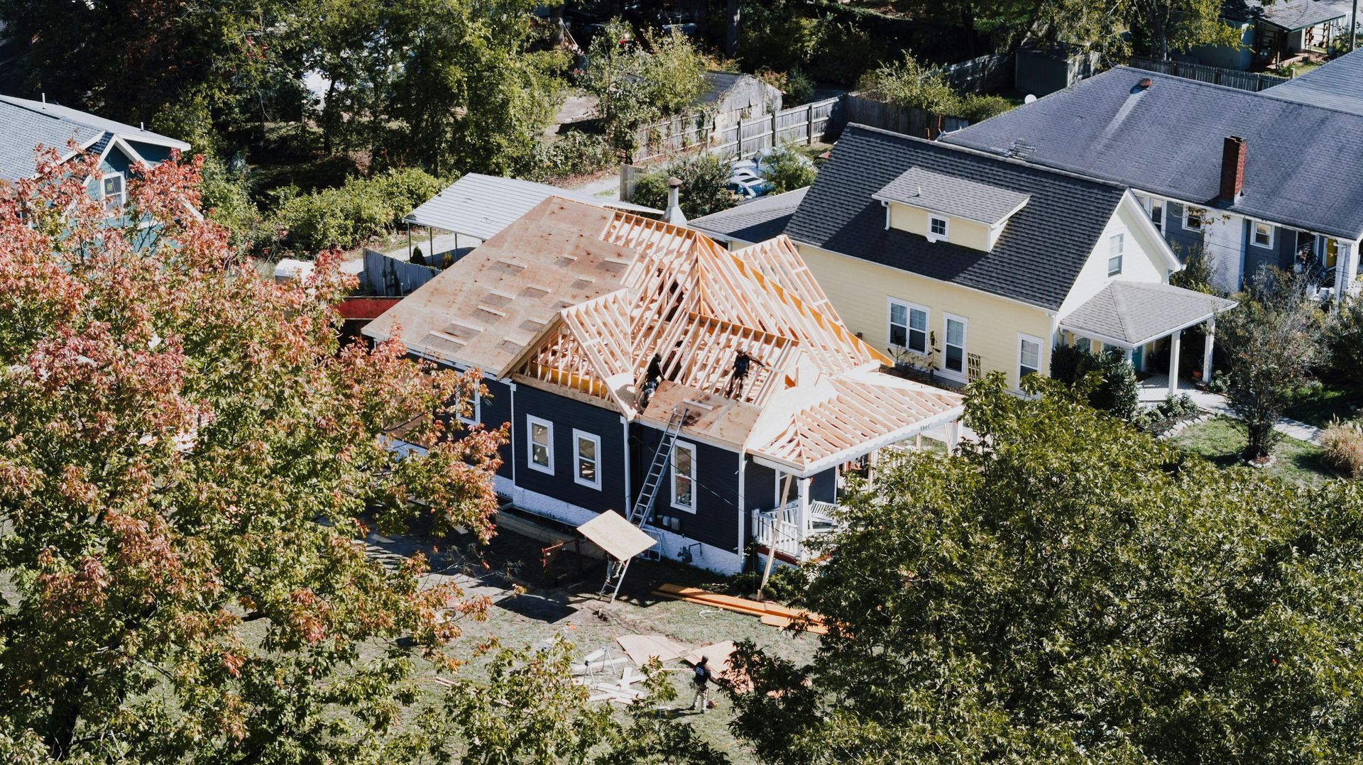 Aerial view of suburban houses with trees, one home under roof repair.