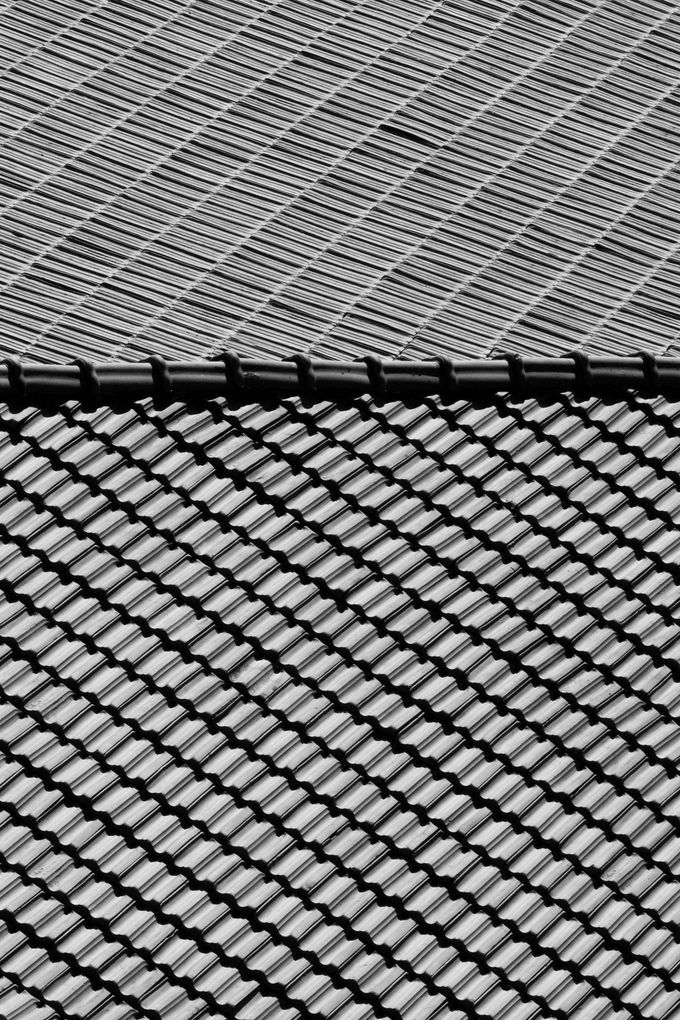 Close-up of woven black mesh over a gray textured background with a horizontal seam across the middle