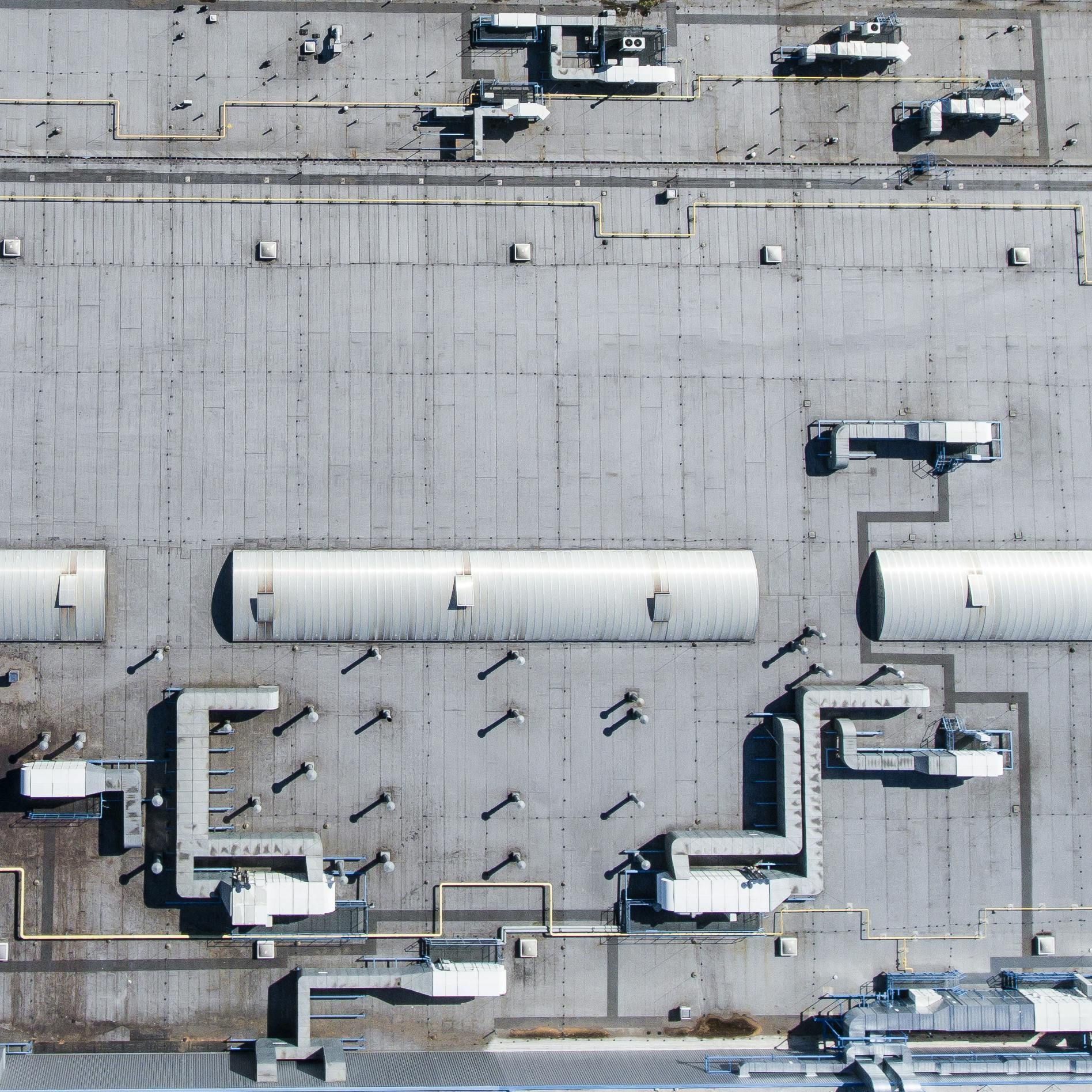 Aerial view of a gray industrial rooftop with vents, pipes, and HVAC units.