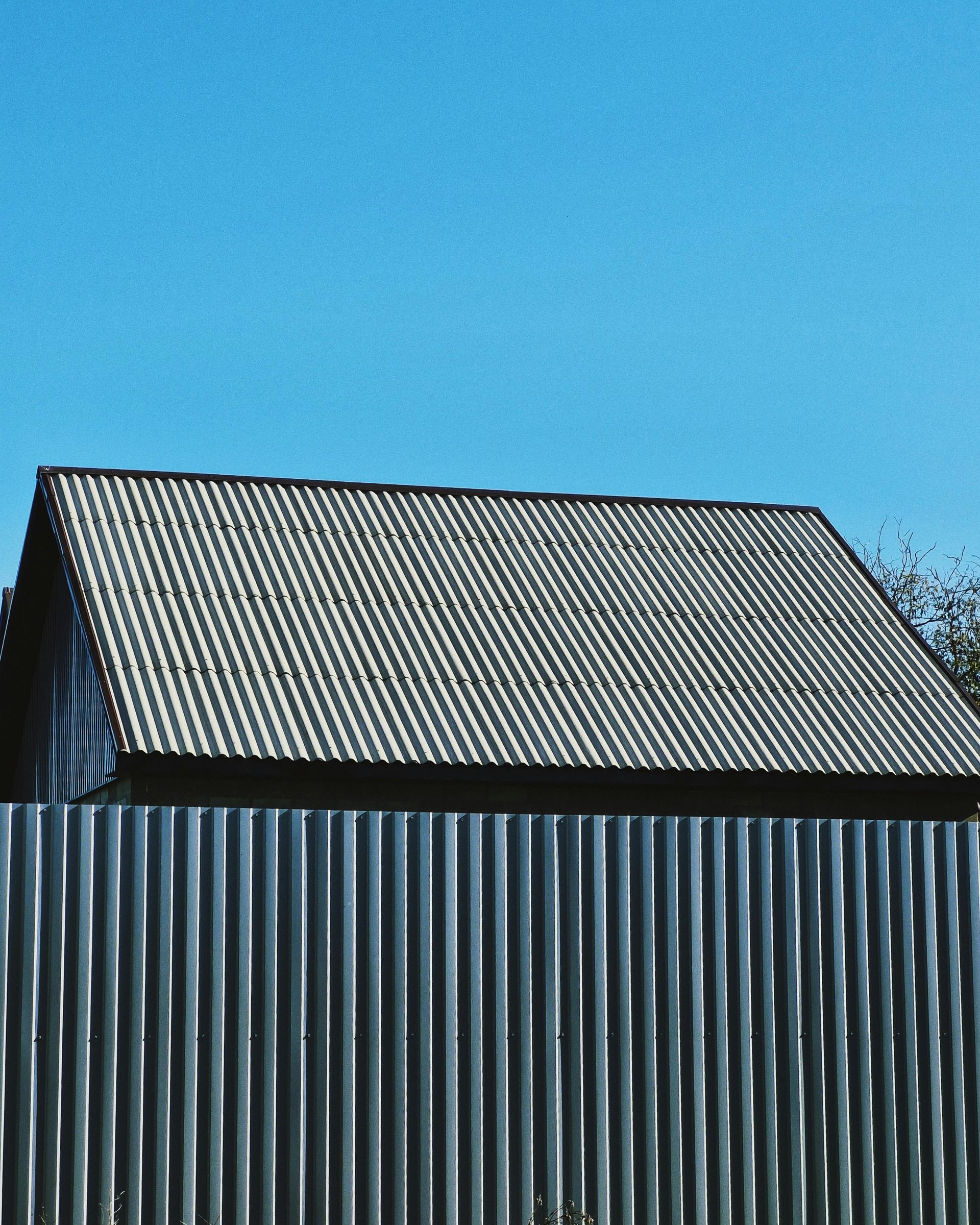 Corrugated metal shed with a gray roof against a clear blue sky