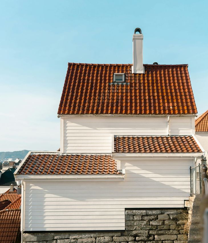 White house with red-tiled roof and chimney against a blue sky