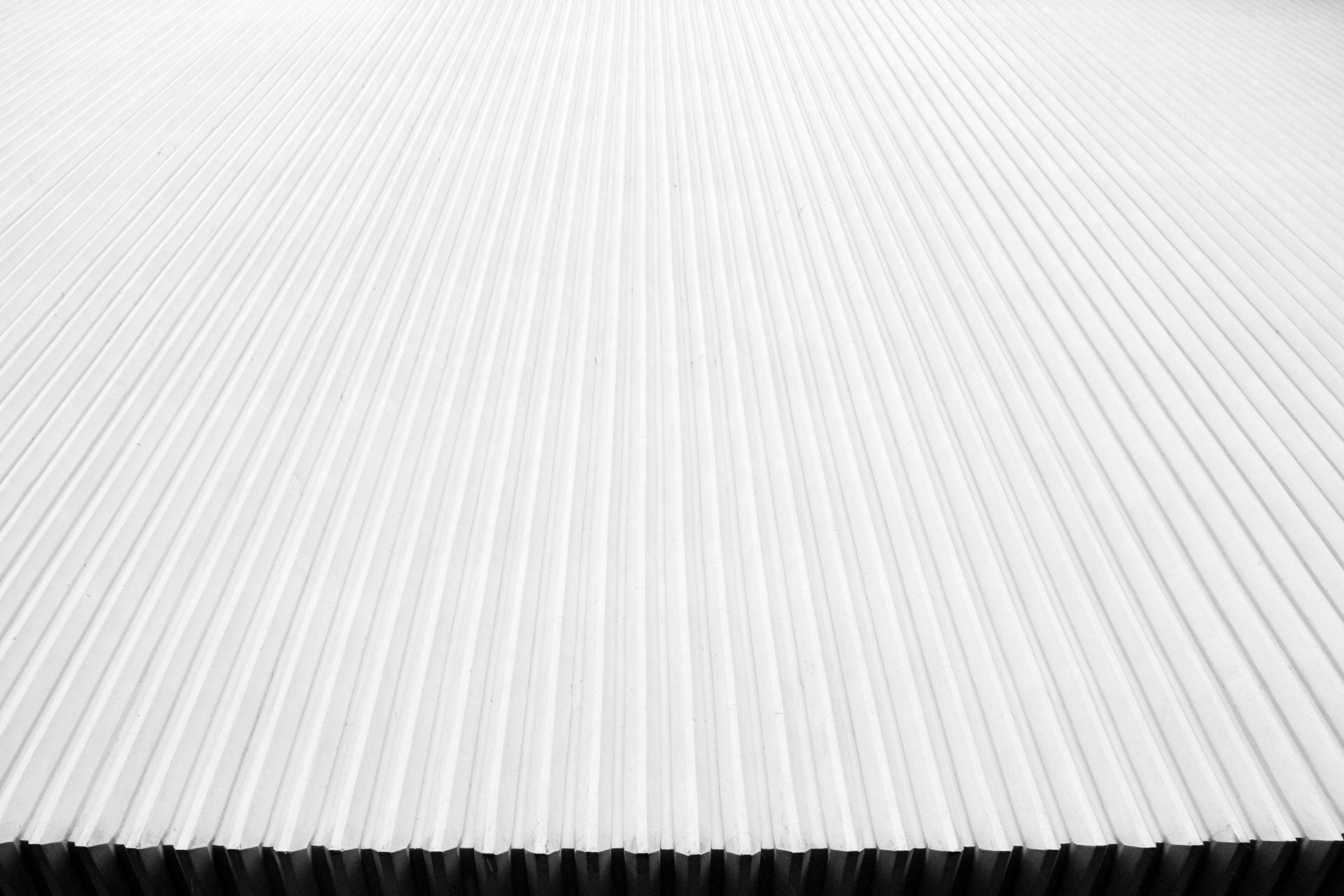 Abstract white ribbed surface with a dark textured edge along the bottom