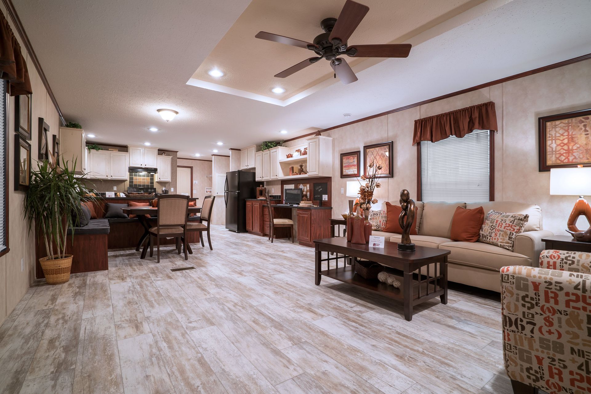 a living room with a couch , chair , coffee table and ceiling fan .