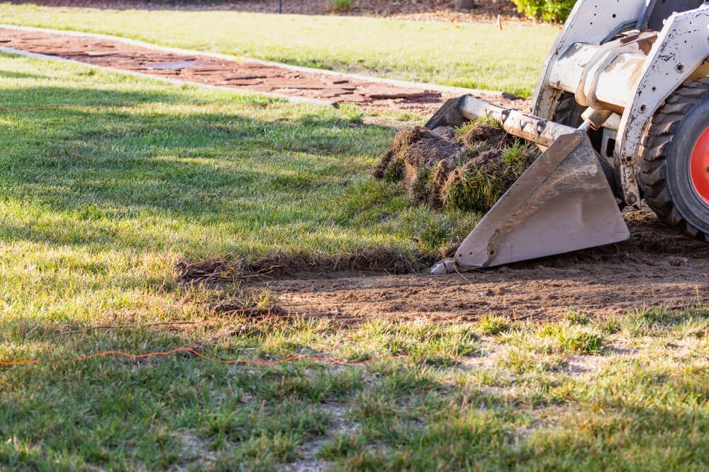 A yellow excavator is sitting on top of a pile of gravel.