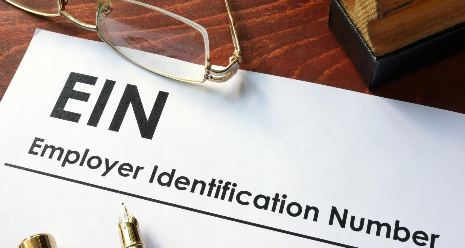 EIN form on a desk with large black letters and a gold paperclip on white paper