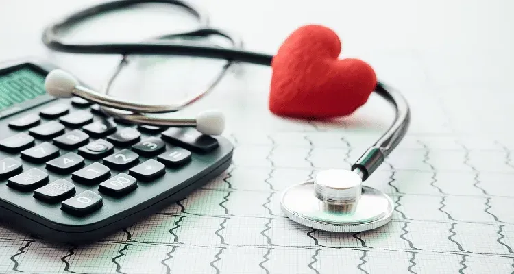 Calculator, stethoscope, and red heart on an ECG chart, symbolizing healthcare costs and heart health