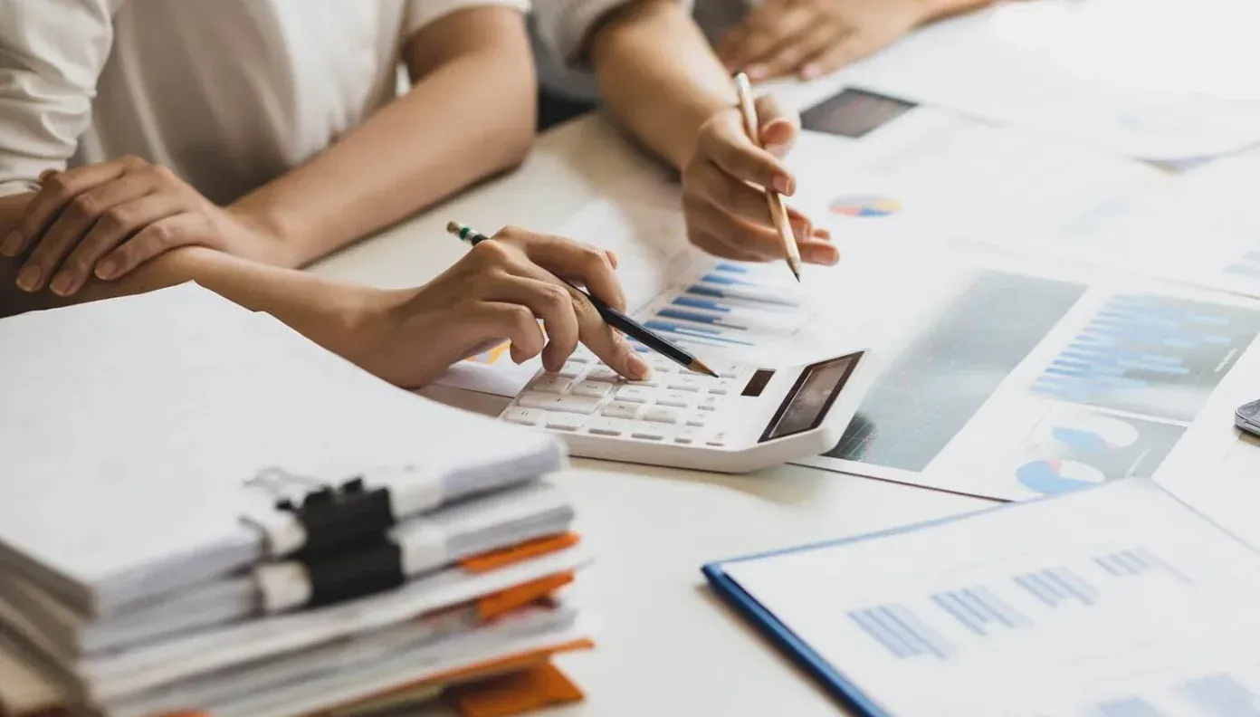 Hands reviewing charts and documents at a bright office meeting table