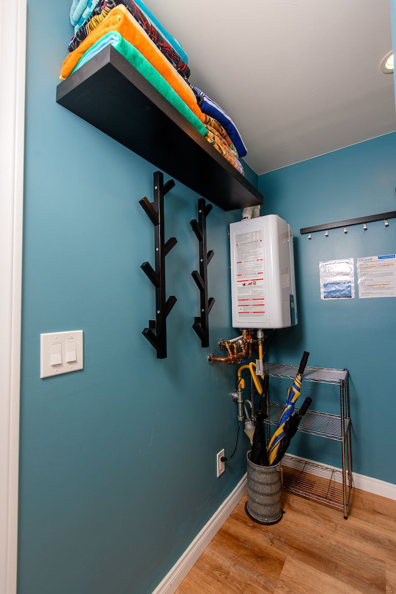 A laundry room with a heater and a shelf filled with towels.